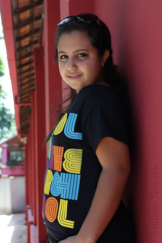 girl leaning on wall with colorful letters t - shirt on