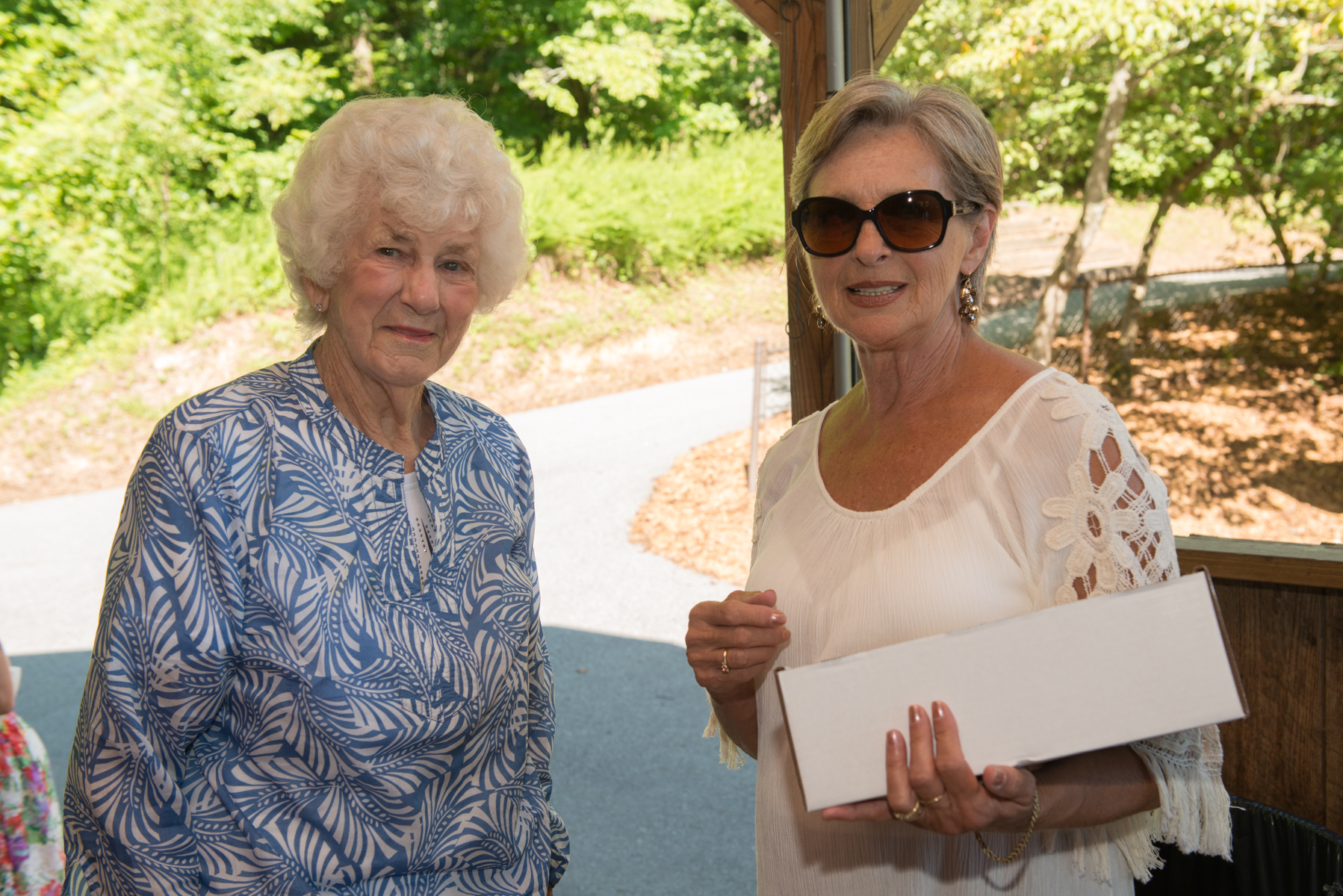 two women are standing together at an outdoor event