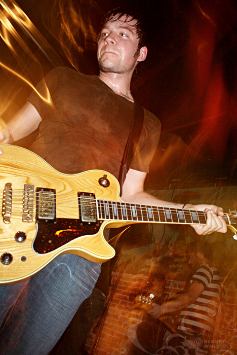 a young man playing an electric guitar on stage