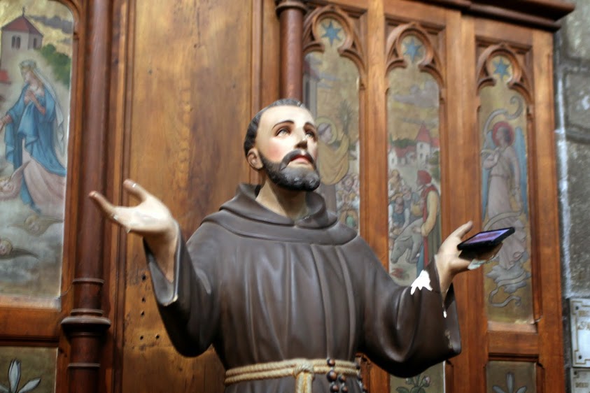 a statue in a church with a priest with his hands raised
