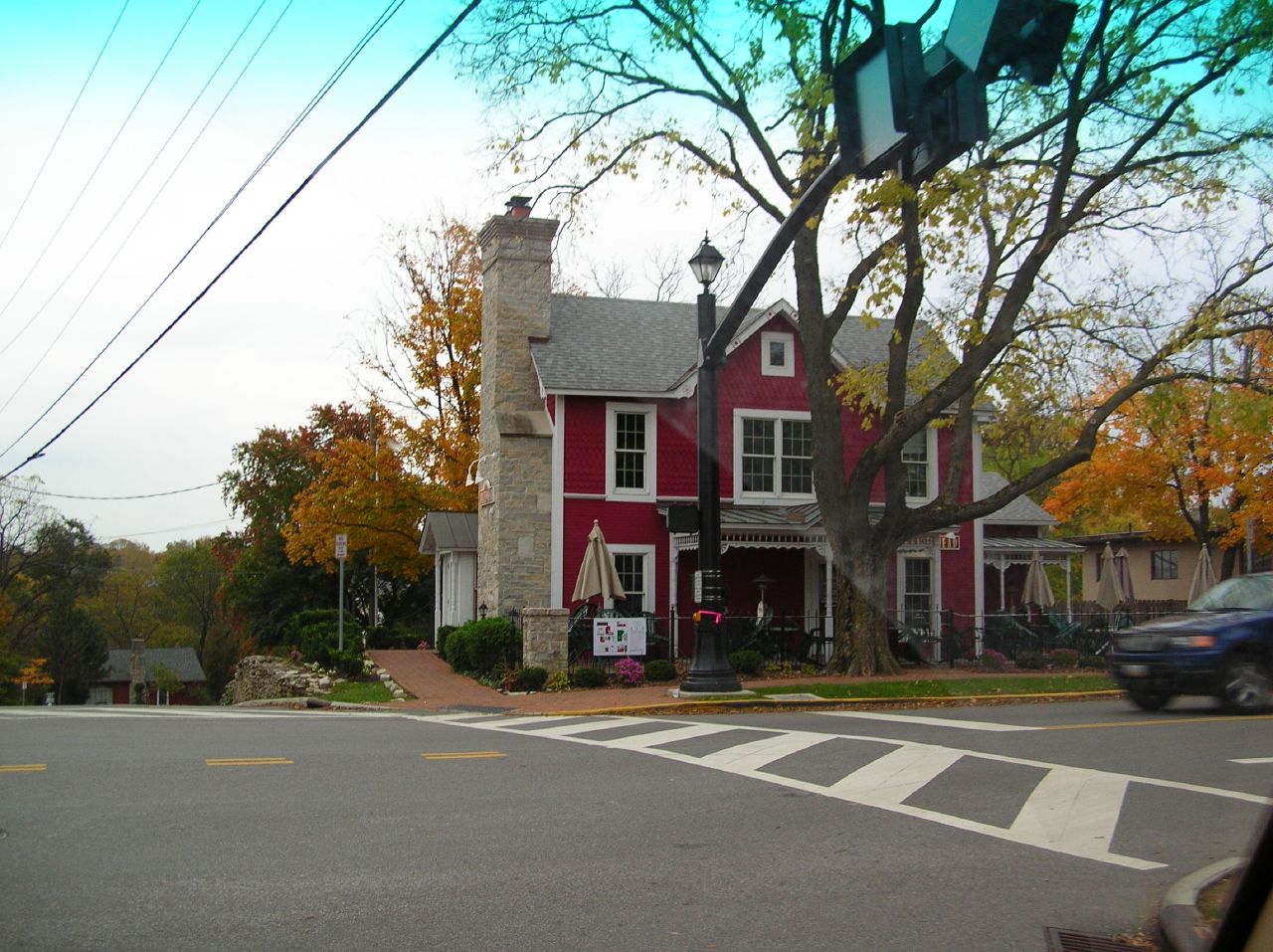 a red house on the corner of a road in the fall