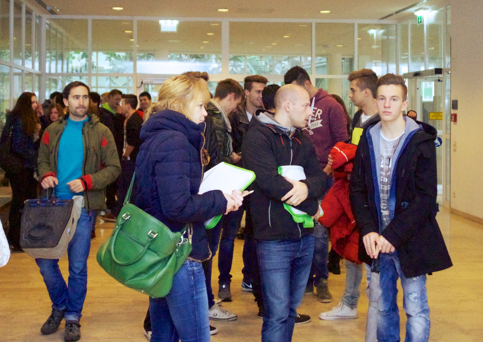 several people stand and wait for information at an airport