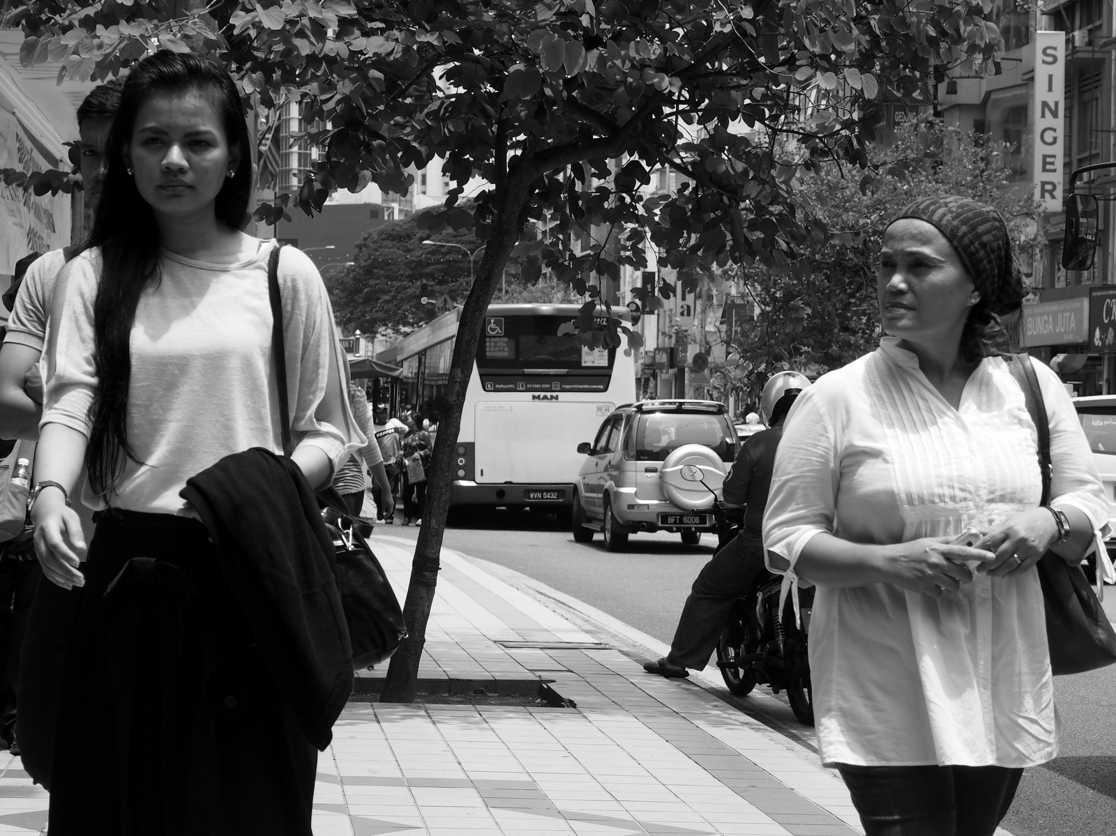 a woman standing on the sidewalk as others walk around