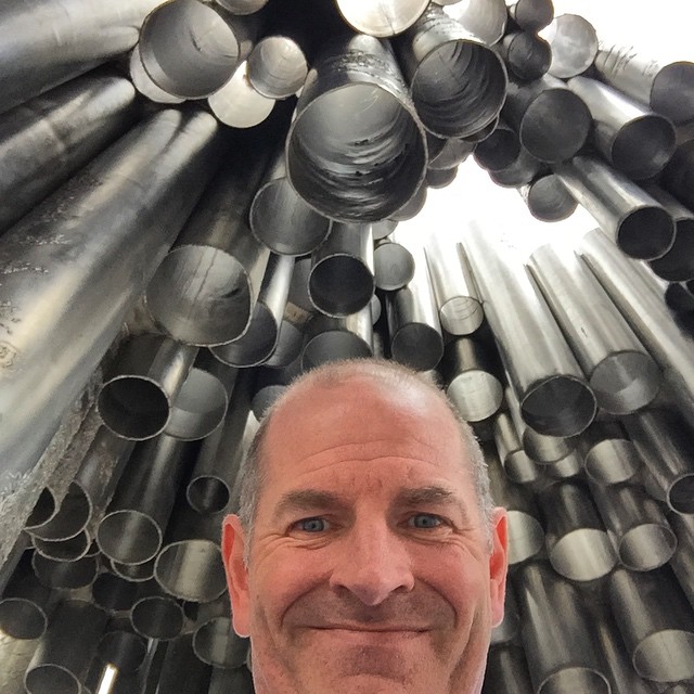 a man stands in front of large metal pipes