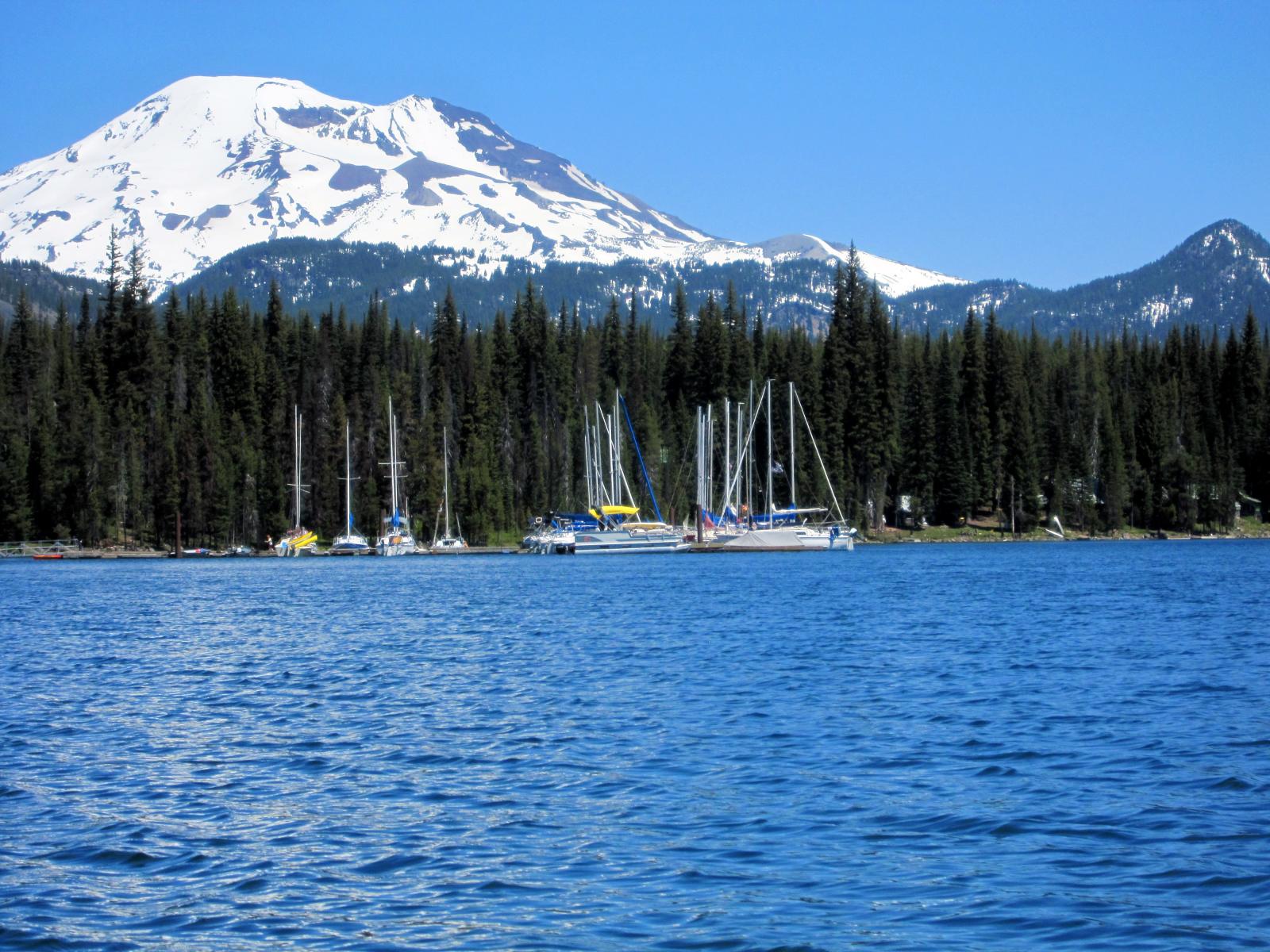 a large lake surrounded by mountains, boats and pine trees