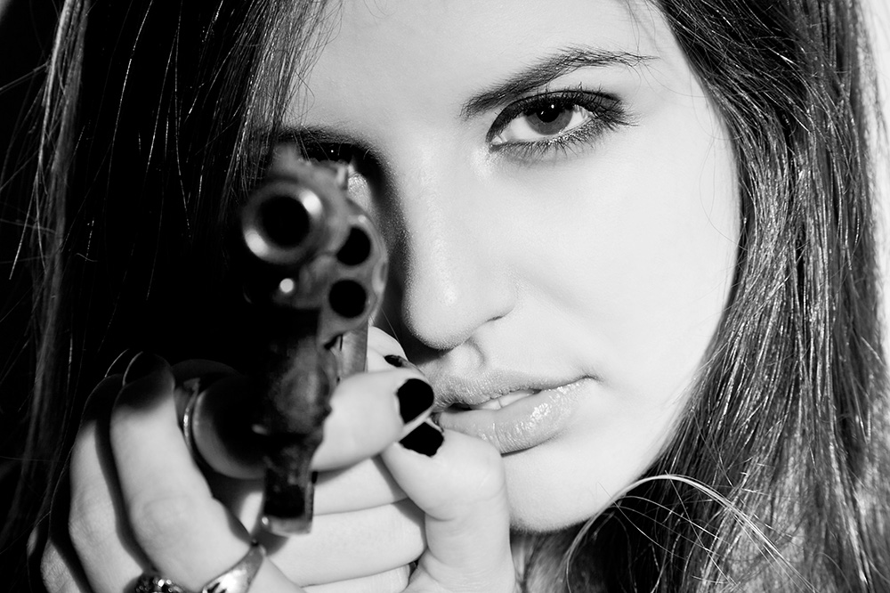 a woman with a gun in her hands looks at the camera