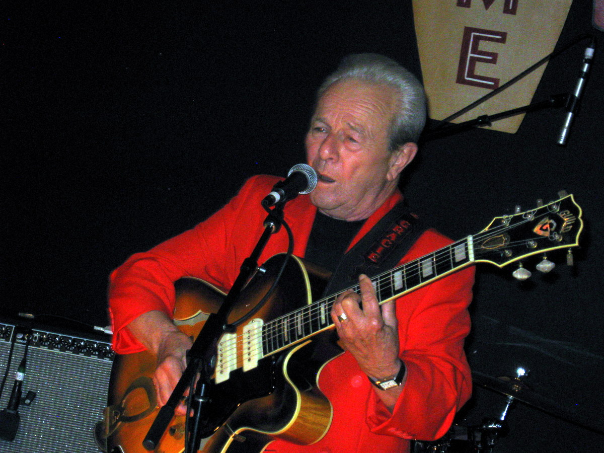 an old man is playing guitar while he sings