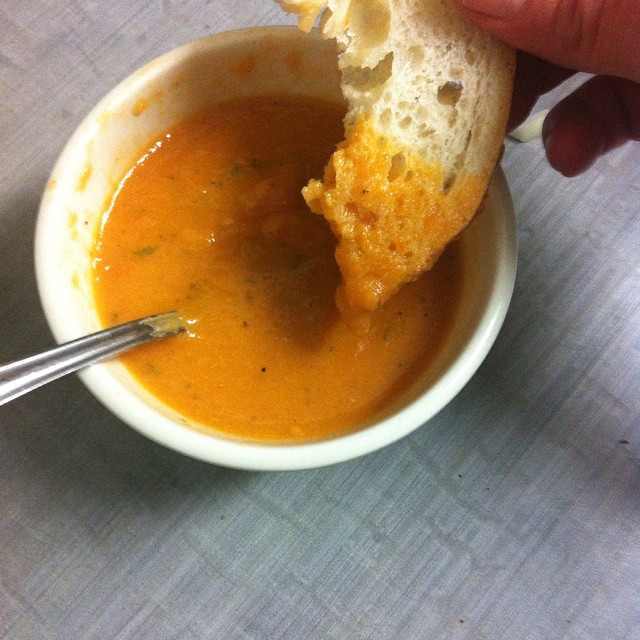a hand is dipping a piece of bread into soup