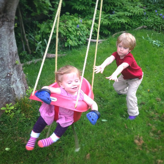 two little s playing in a pink swing