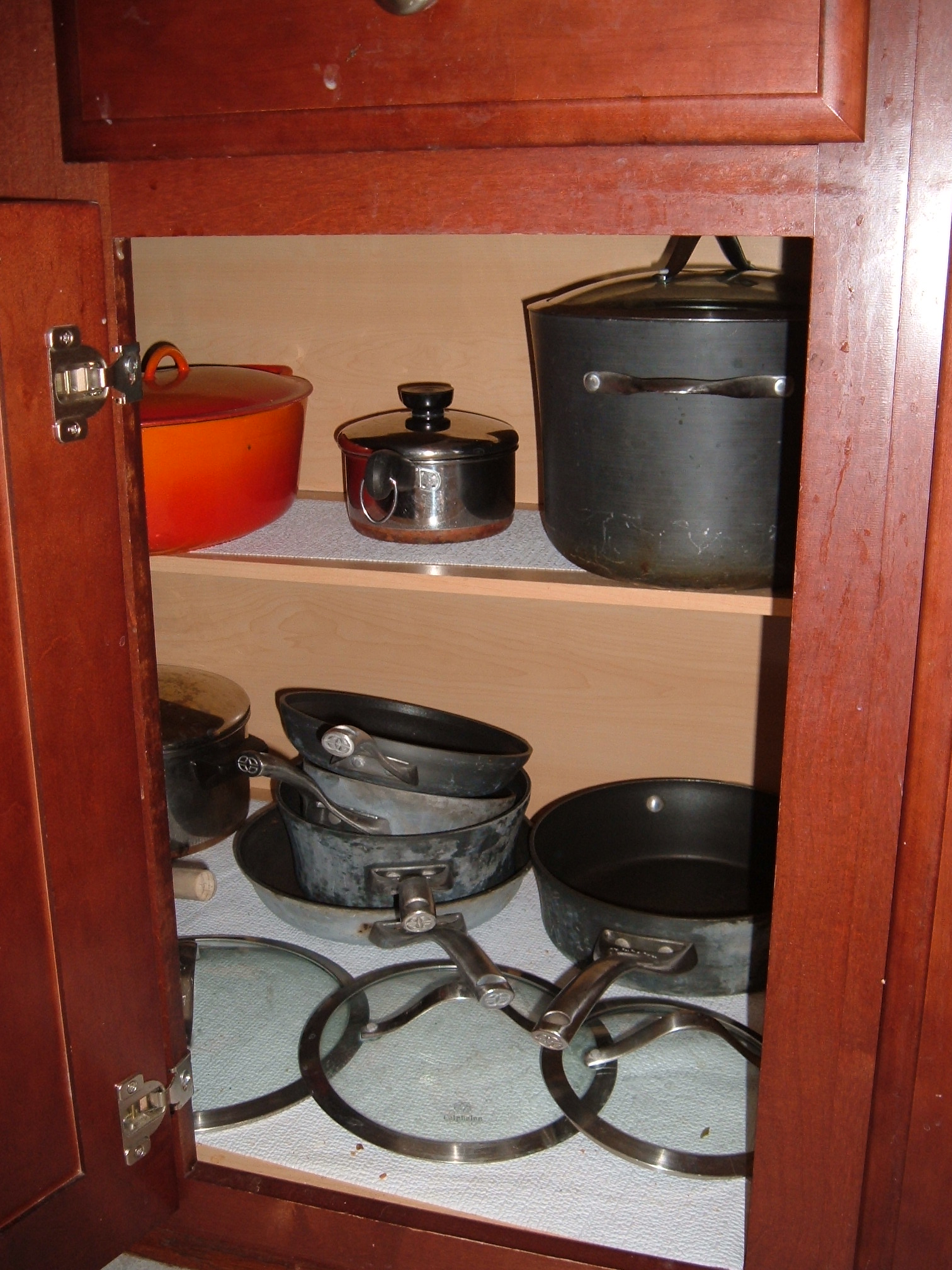 a view from behind some pans on the shelf in the kitchen