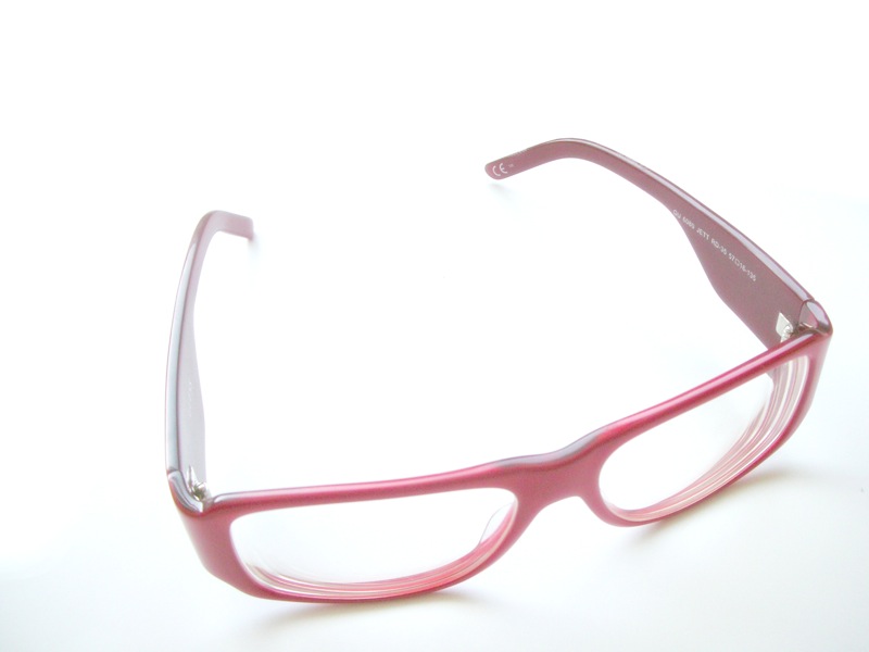 pink glasses on a white surface with a reflection