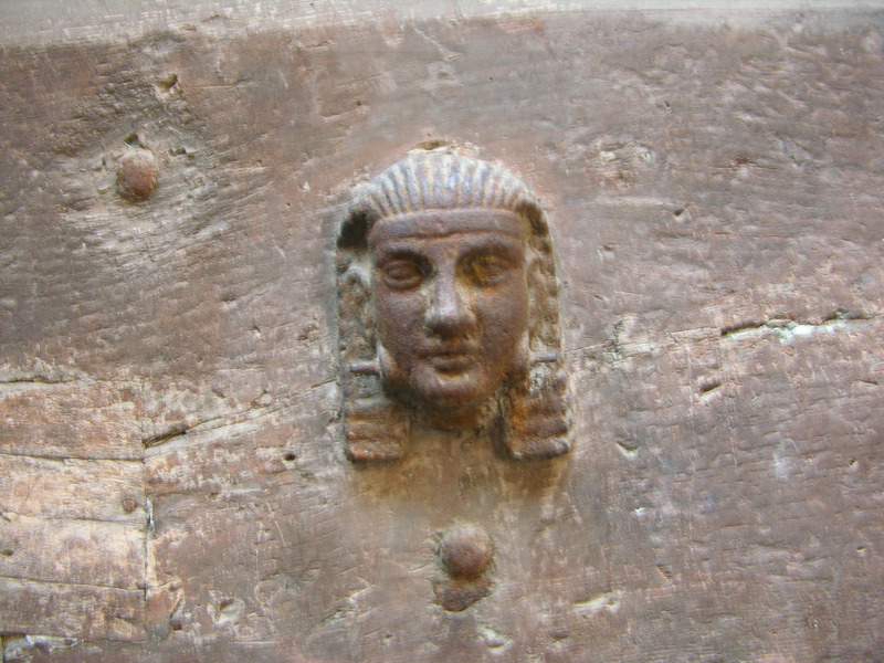 ancient head and earrings attached to an old, weathered wall