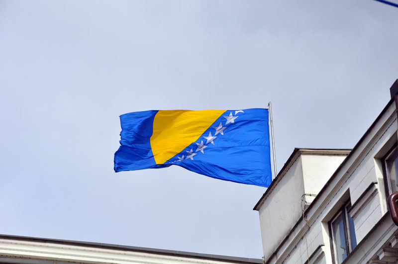 a flag flying outside of a building with clock on a tower