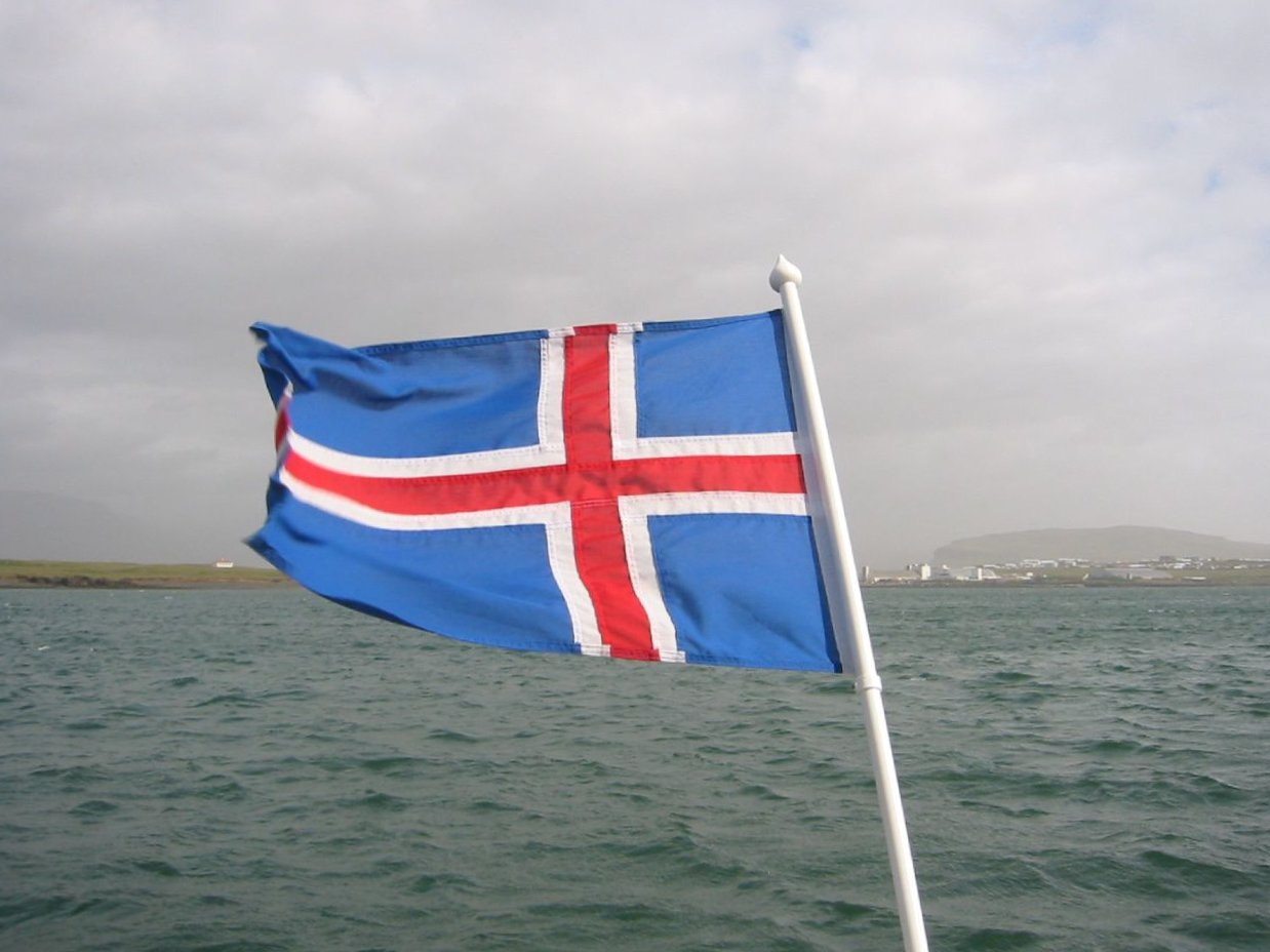 a flag flying from a boat in the middle of the ocean