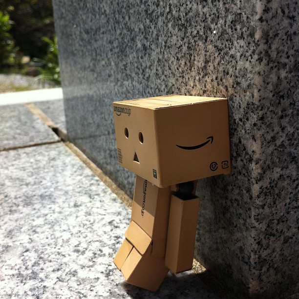 a cardboard box character leaning against a wall