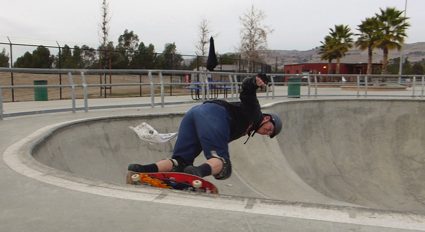 a man riding up the side of a cement bowl with a skateboard