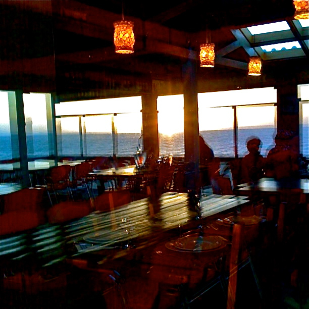 a group of people sitting and standing in a room with lots of windows