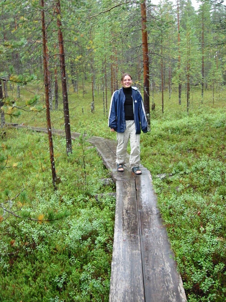man posing on old wooden footbridge in forest