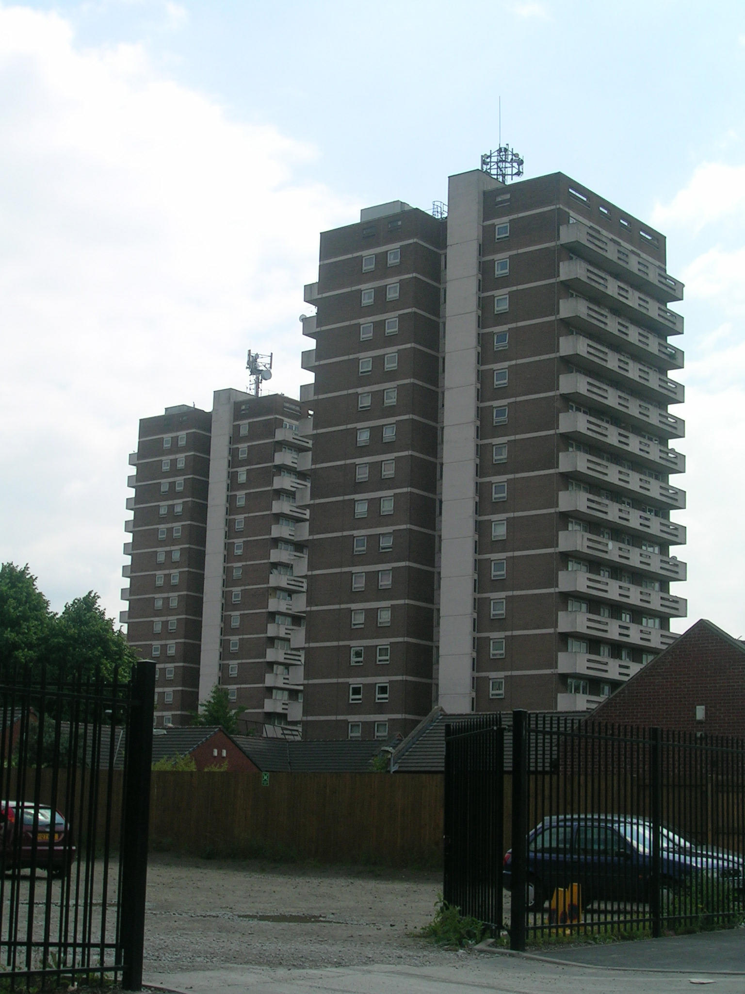 cars parked in the foreground behind tall brown buildings