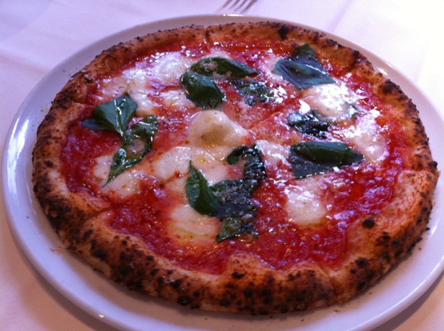 a pizza sitting on top of a white plate next to a knife and fork