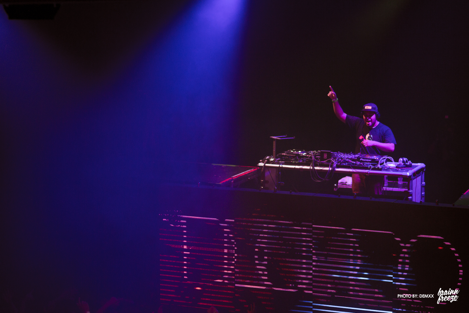 dj in front of purple and blue lights playing music