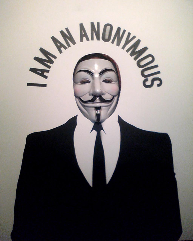 man in black suit with fake mask with words on wall