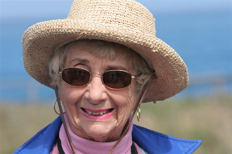 the older woman in the hat and blue jacket has earrings on