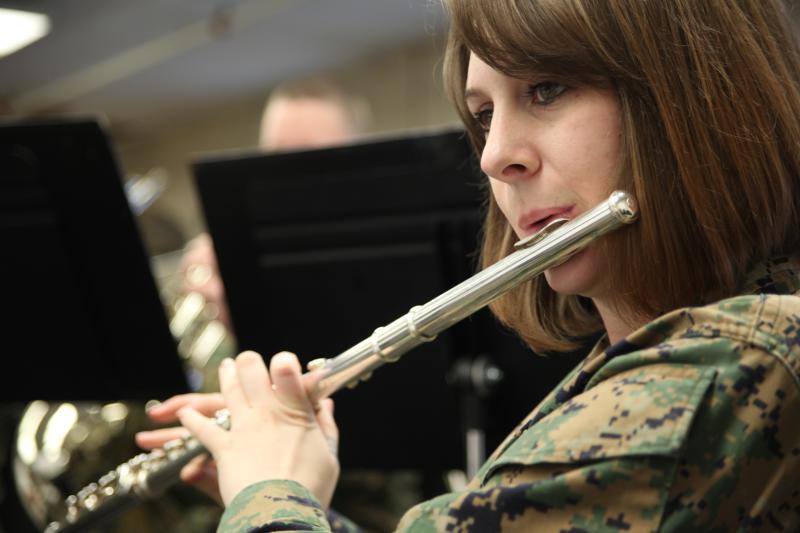 a woman wearing military uniforms playing a silver instrument