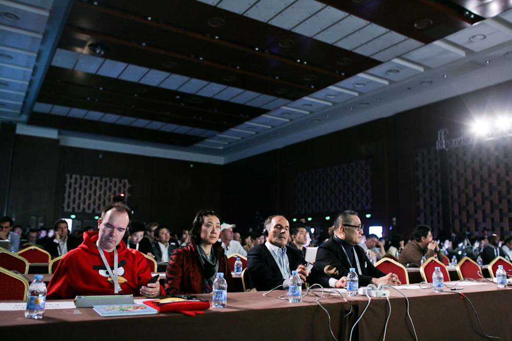 a group of people at a conference, one wearing a red uniform