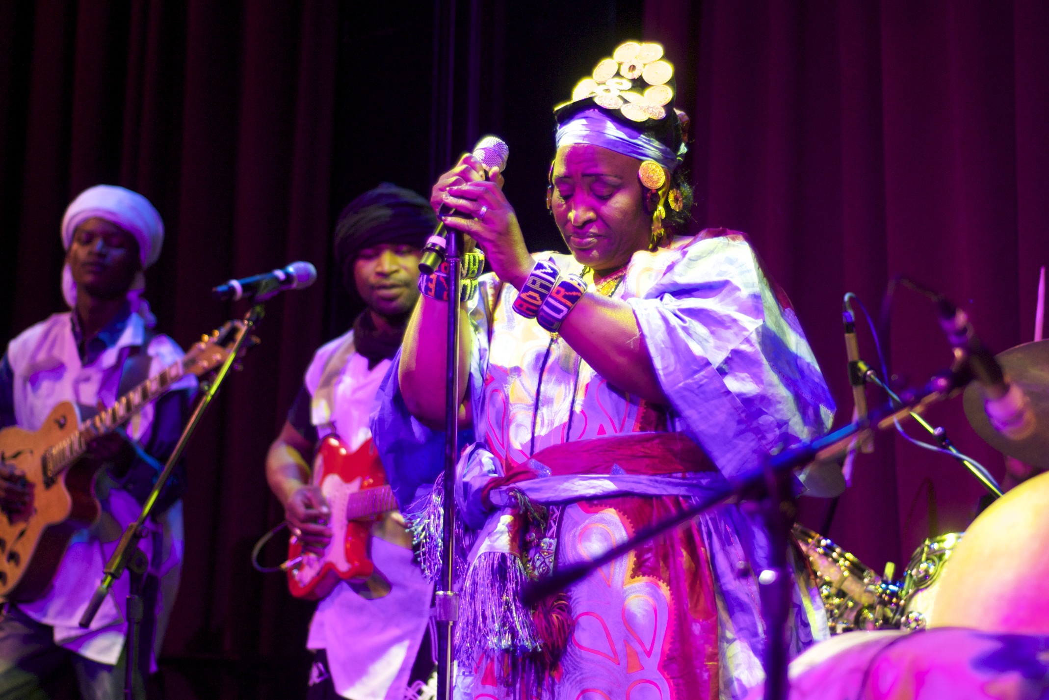 the woman in the purple dress is playing guitar