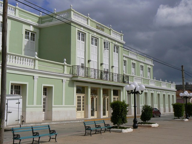 two empty benches in front of a mint green building
