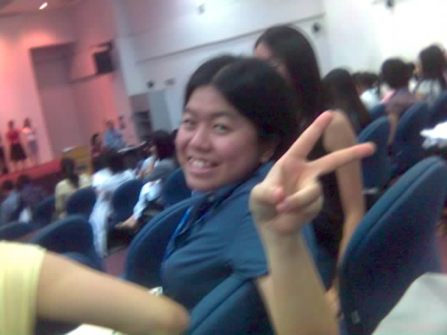 an asian woman in a blue shirt gives the peace sign