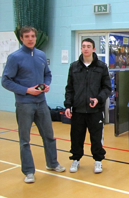 two men standing on a basketball court with one holding an object