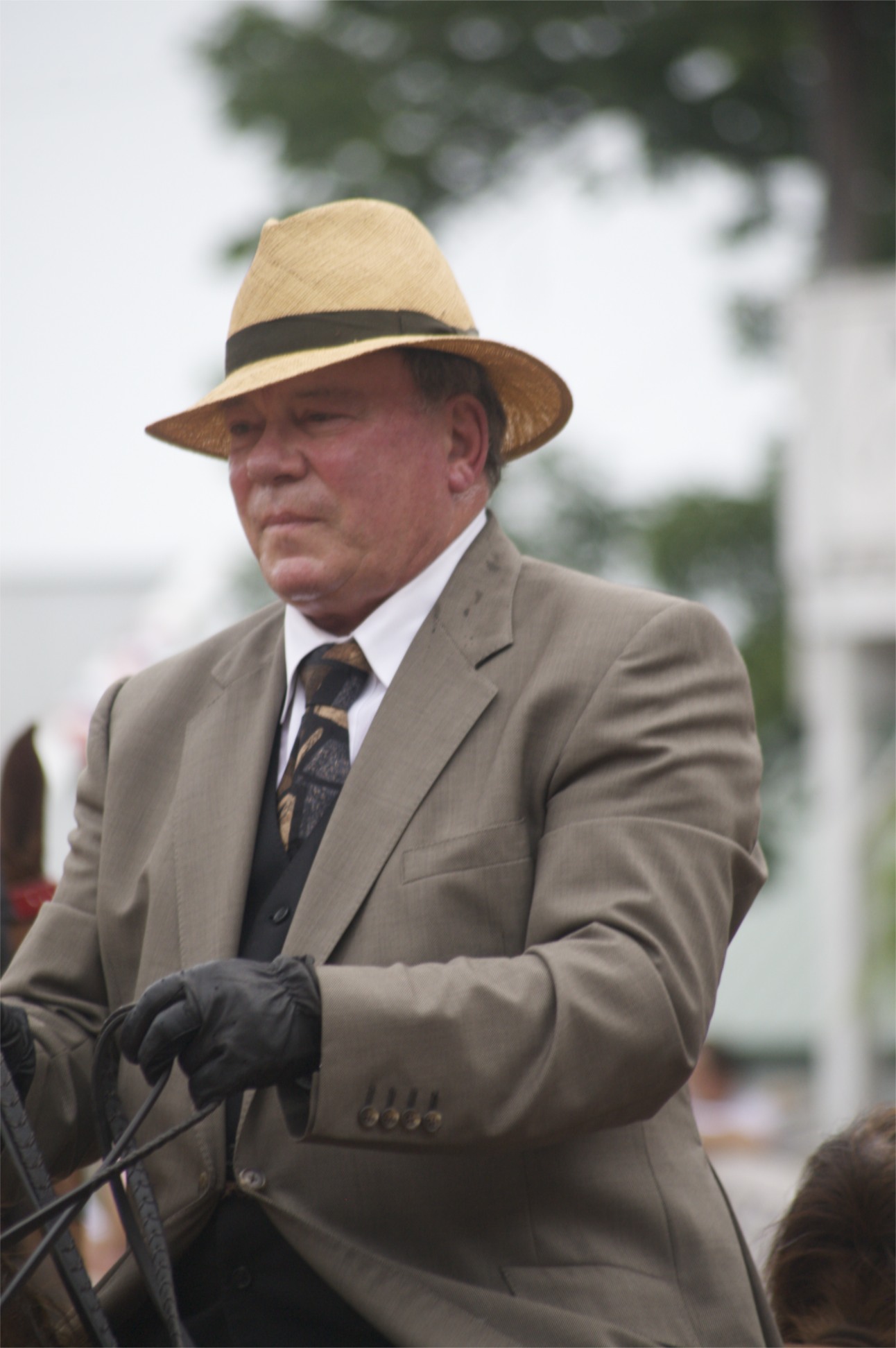 a man with a hat on holding a black horse