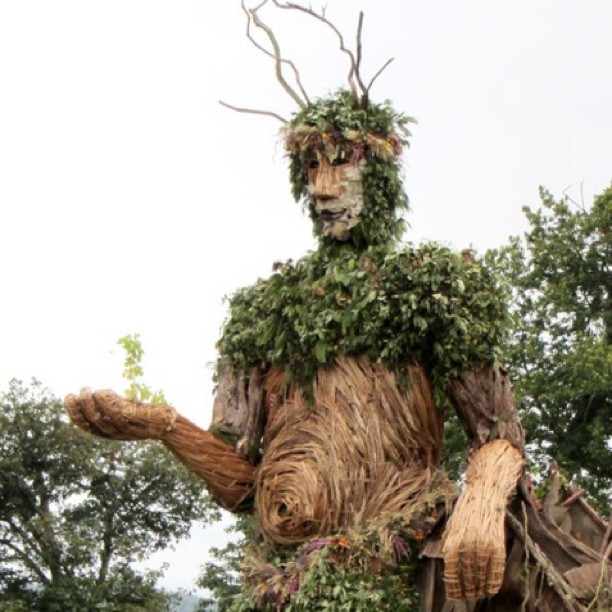 a man made of tree nches in front of trees