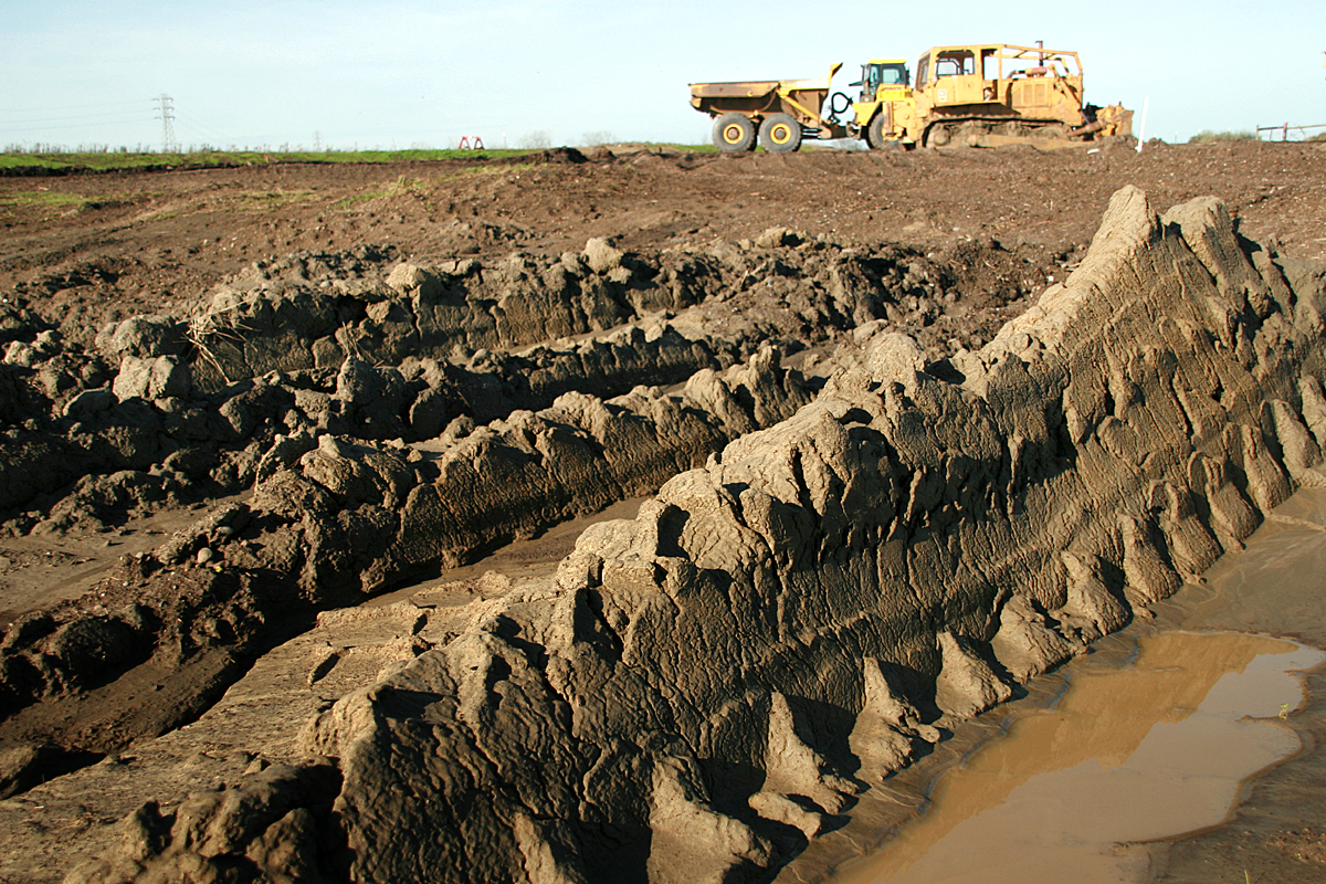 the bulldozer is moving over the muddy area