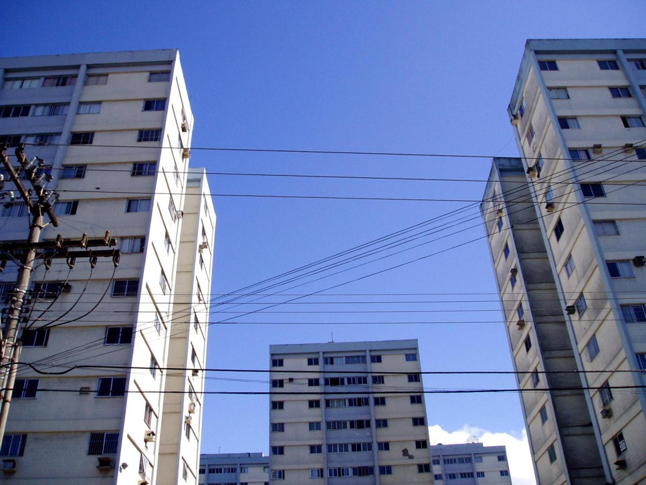 apartment buildings in a large city with electric wires in the foreground