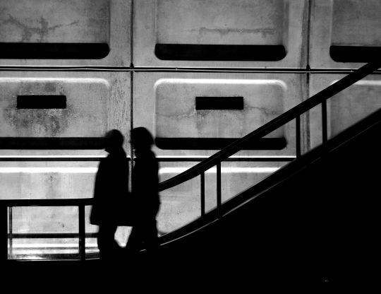 silhouette of two people walking up some stairs