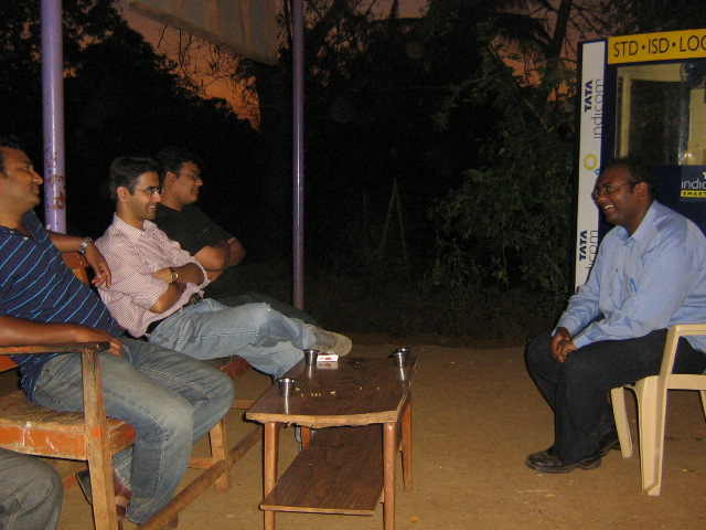 three men sitting down outside talking to each other