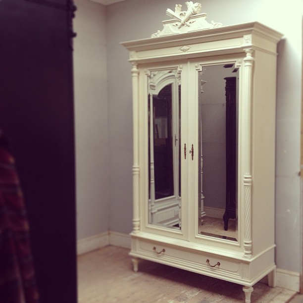 a white cabinet with mirrored doors inside a room