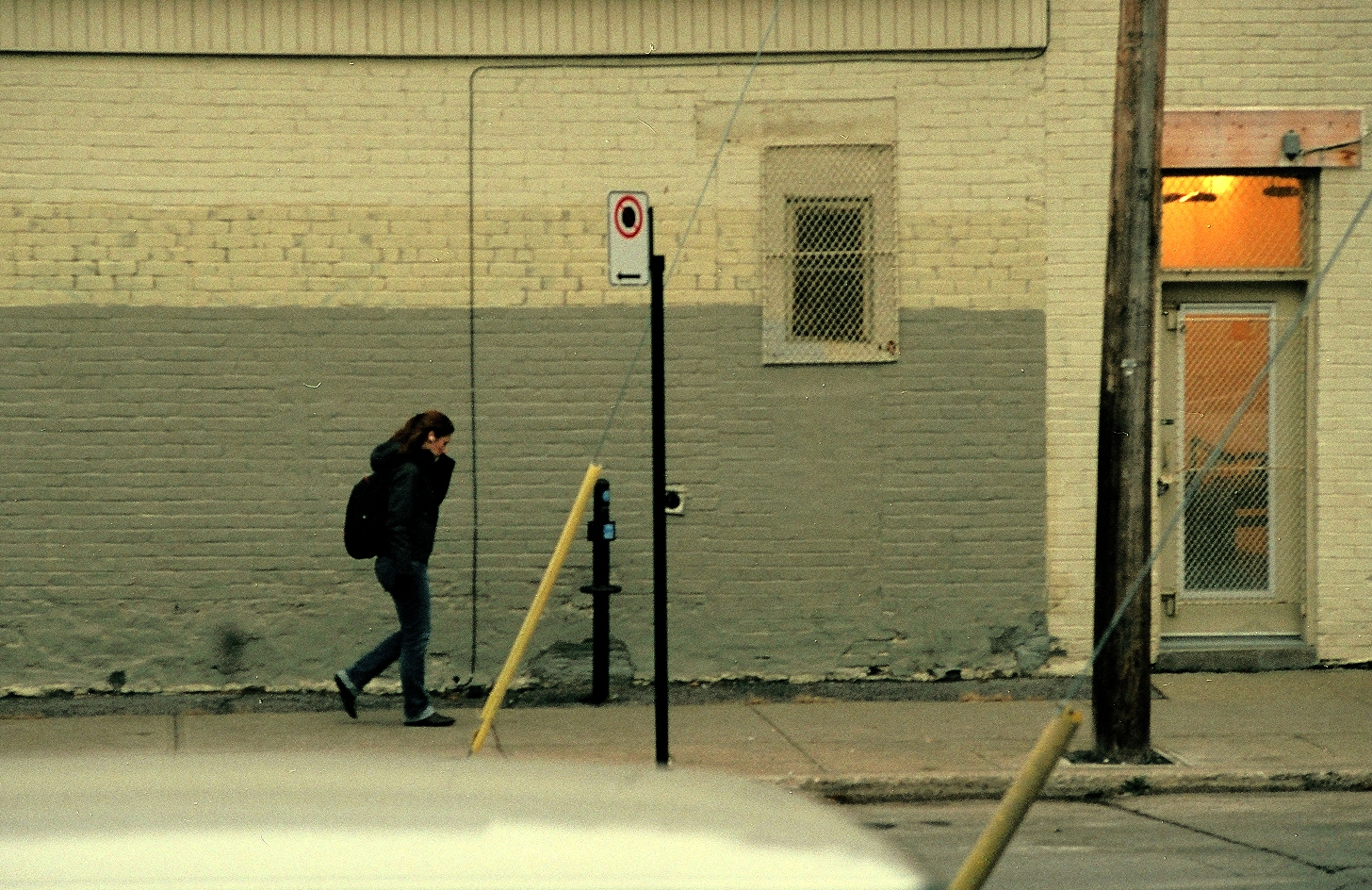 a man is walking down the street next to a parking meter