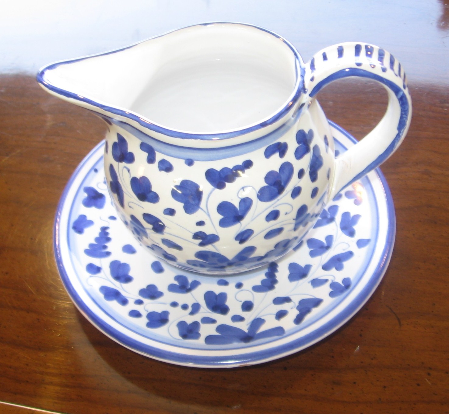 a ceramic pitcher and saucer on a wooden table