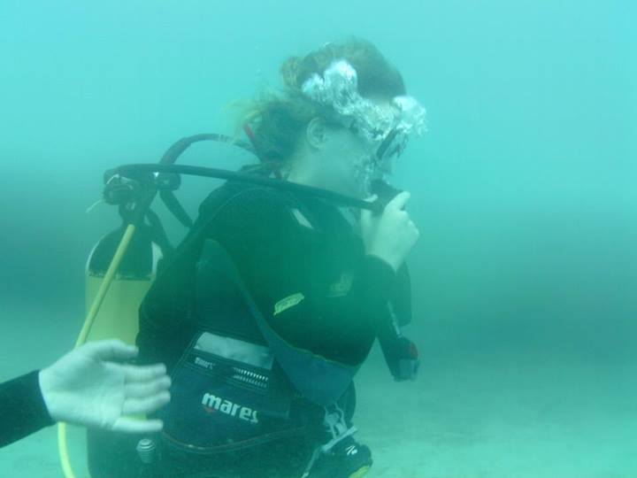 a woman diving in the ocean, with her equipment