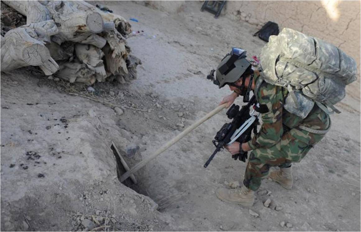 a soldier looks at a shovel in the dirt