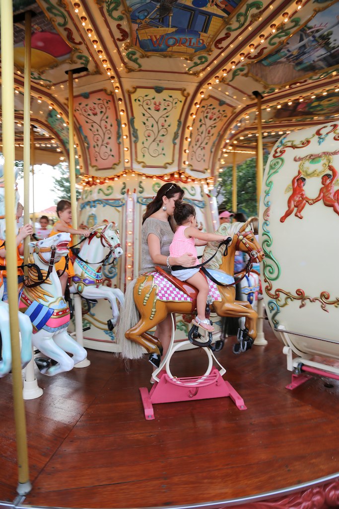 people riding the merry go round on a wooden carousel