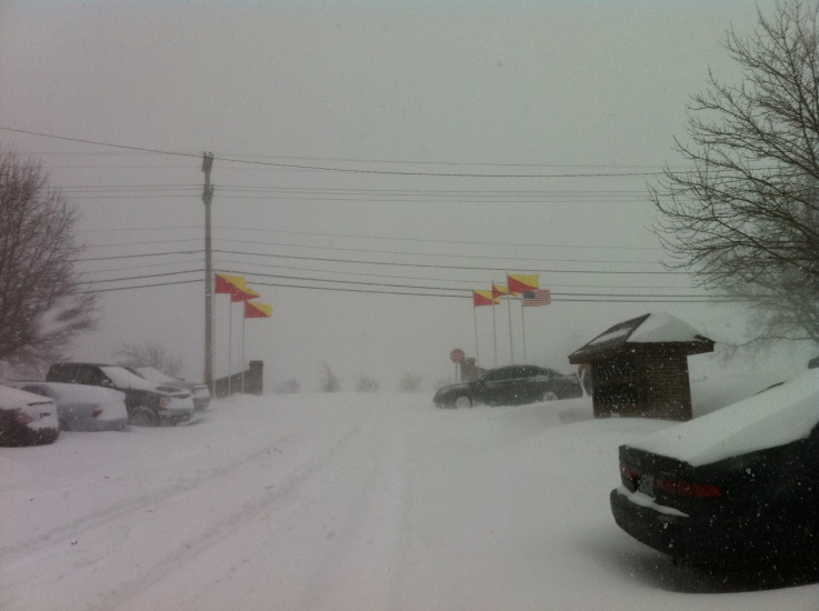 snow and cars on a street next to flags
