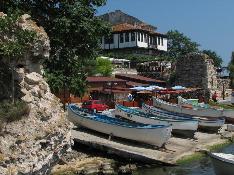 a line of boats parked at a dock next to a small rock structure