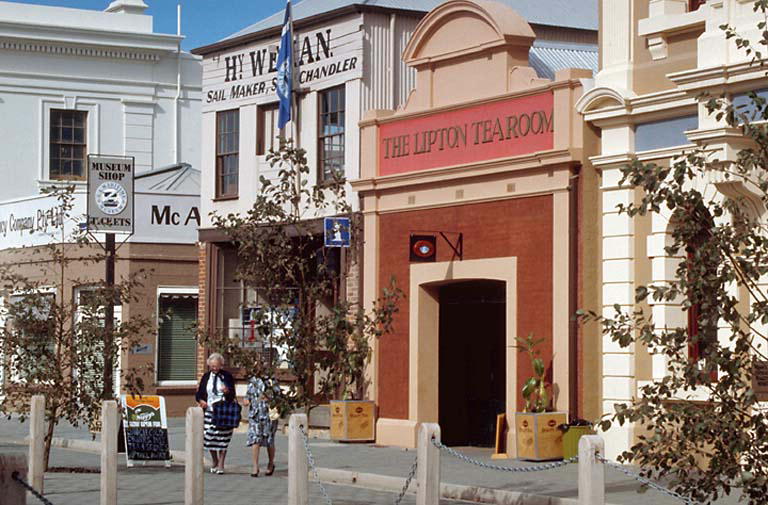 the woman is walking past a few shops