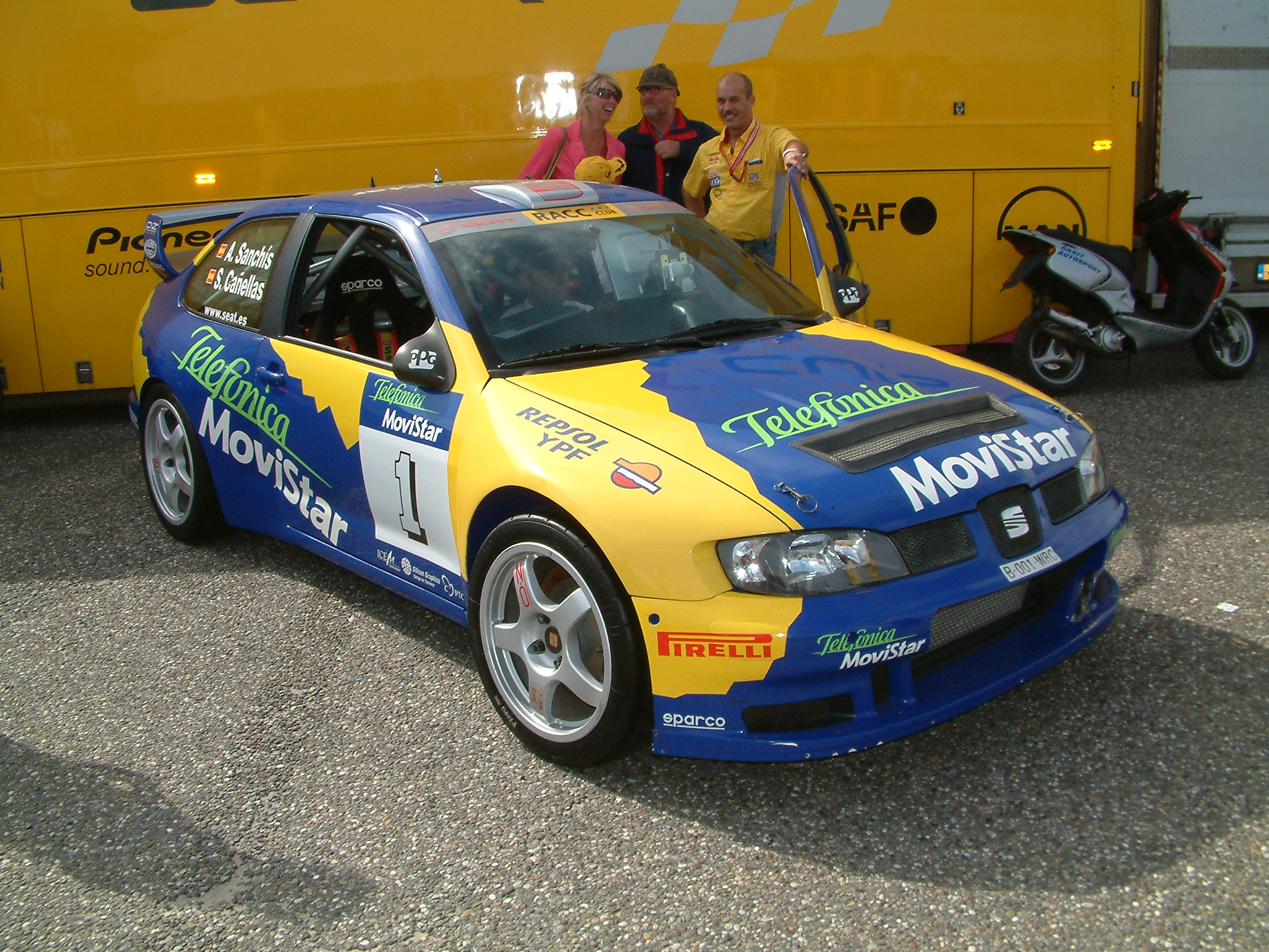 an older model car in front of a yellow truck