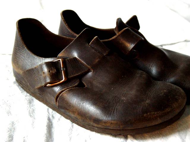 brown shoes with a gold buckle sitting on a white surface
